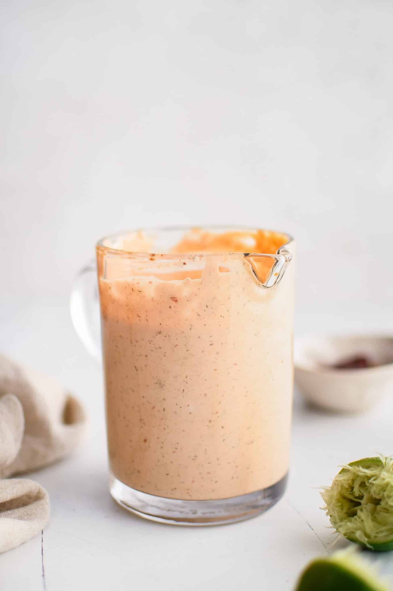 Small glass pitcher filled with thick and creamy chipotle ranch dressing.