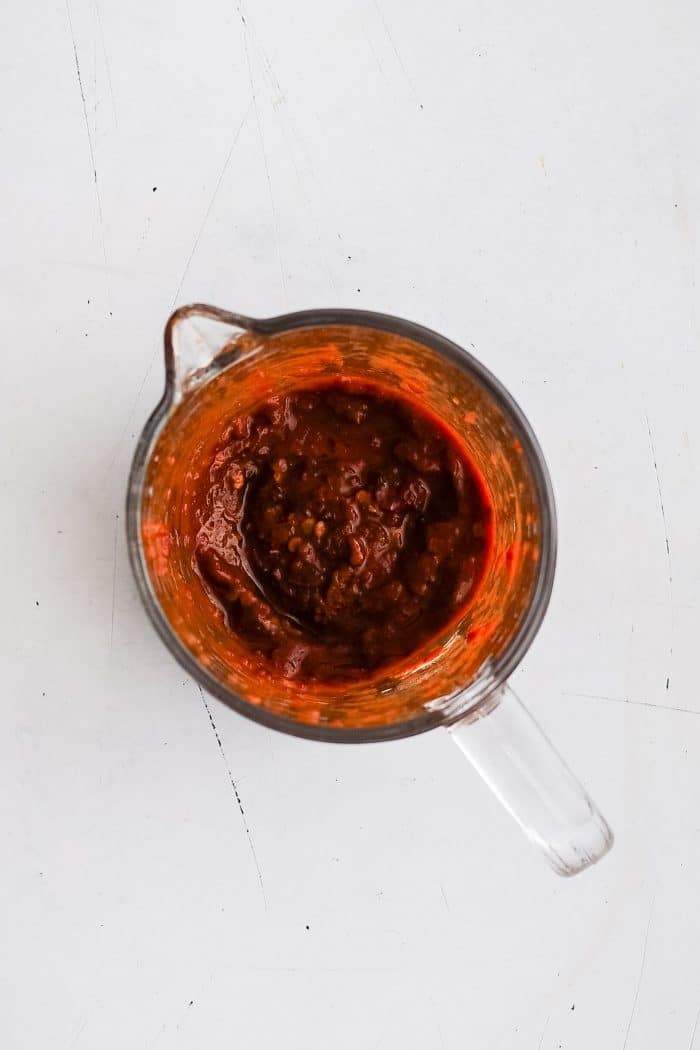 Glass measuring cup filled with blended chipotle peppers in adobo sauce and lime juice.