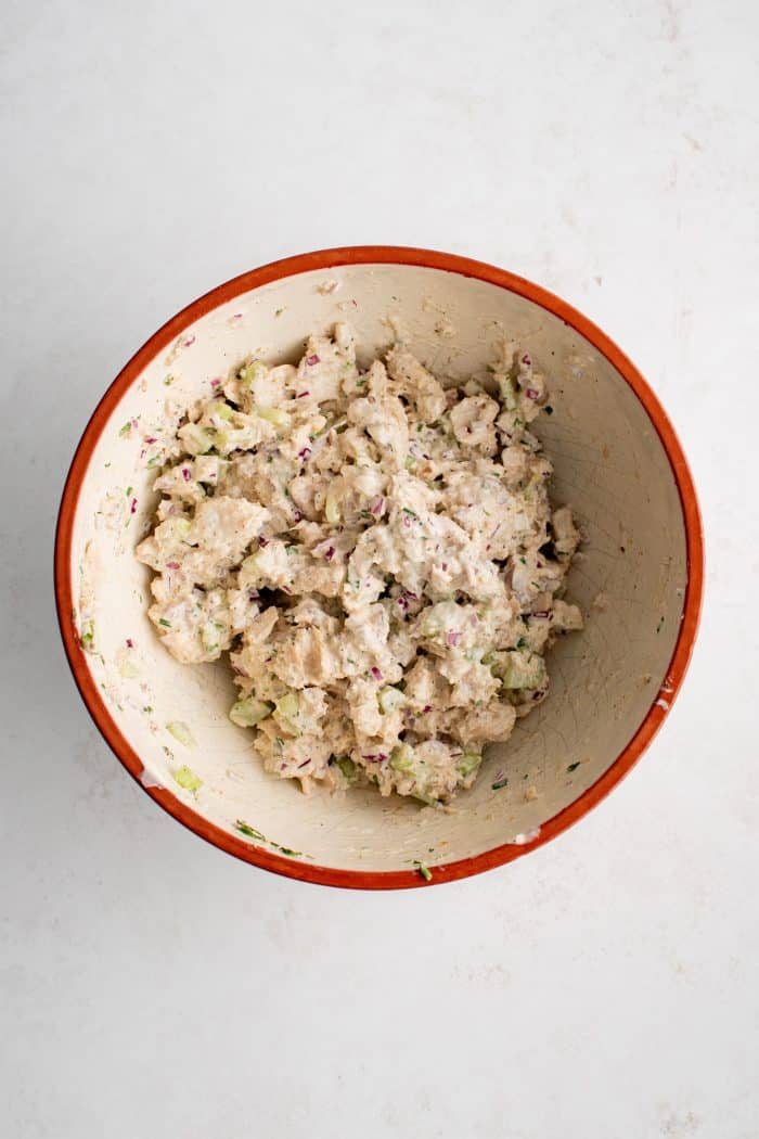 Chilled canned salmon salad made with mayonnaise and stone ground mustard in a medium mixing bowl.