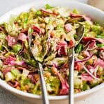 Large white bowl filled with the famous la scala salad that consists of chopped lettuce, salami, chickpeas, mozzarella cheese, and red onion tossed in a tangy dijon vinaigrette.