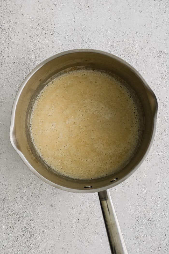 A medium saucepan filled with whisked together melted butter, olive oil, and all-purpose flour (roux).