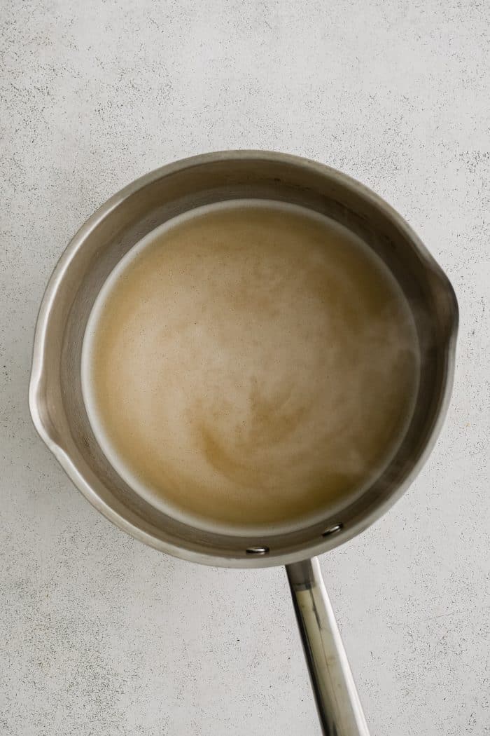 A medium saucepan filled with whisked together melted butter, olive oil, all-purpose flour, and chicken broth.