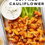 Pinterest pin featuring an overhead photo of baked buffalo cauliflower florets in a small metal tray lined with parchment paper, garnished with chopped green chives and served with bright green celery sticks and a white ramekin of creamy ranch dressing. A white text overlay at the top reads โeasy super bowl appetizer!โ and bold black text reads โBEST BAKED BUFFALO CAULIFLOWER.โ The words โthe forked spoonโ appear at the bottom of the pin.