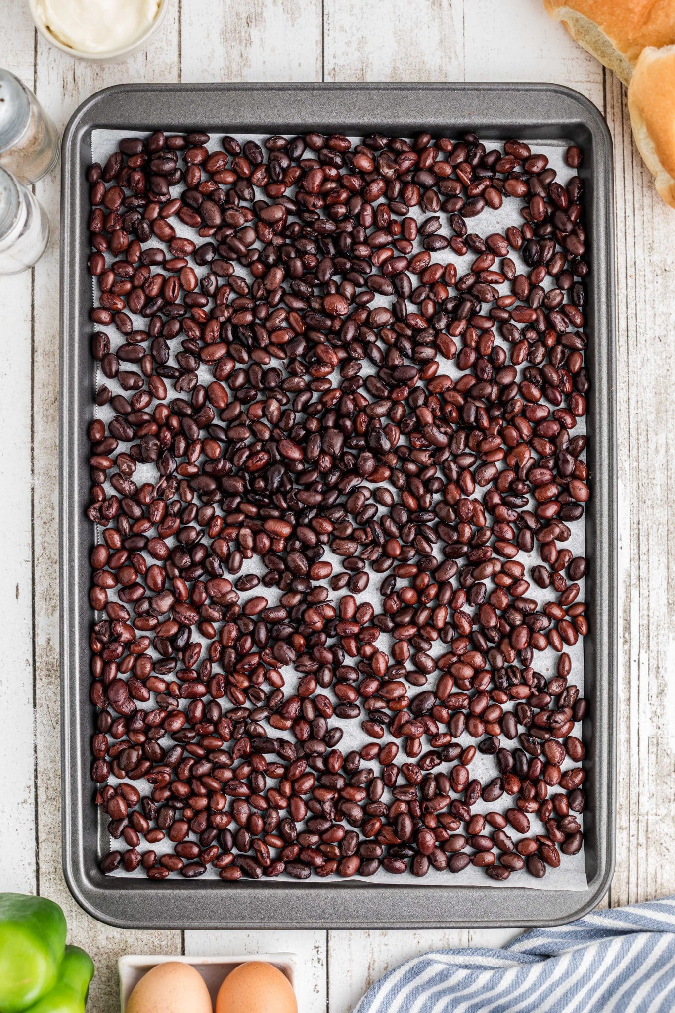 Drained and rinsed canned black beans laid over a large baking sheet with parchment paper.