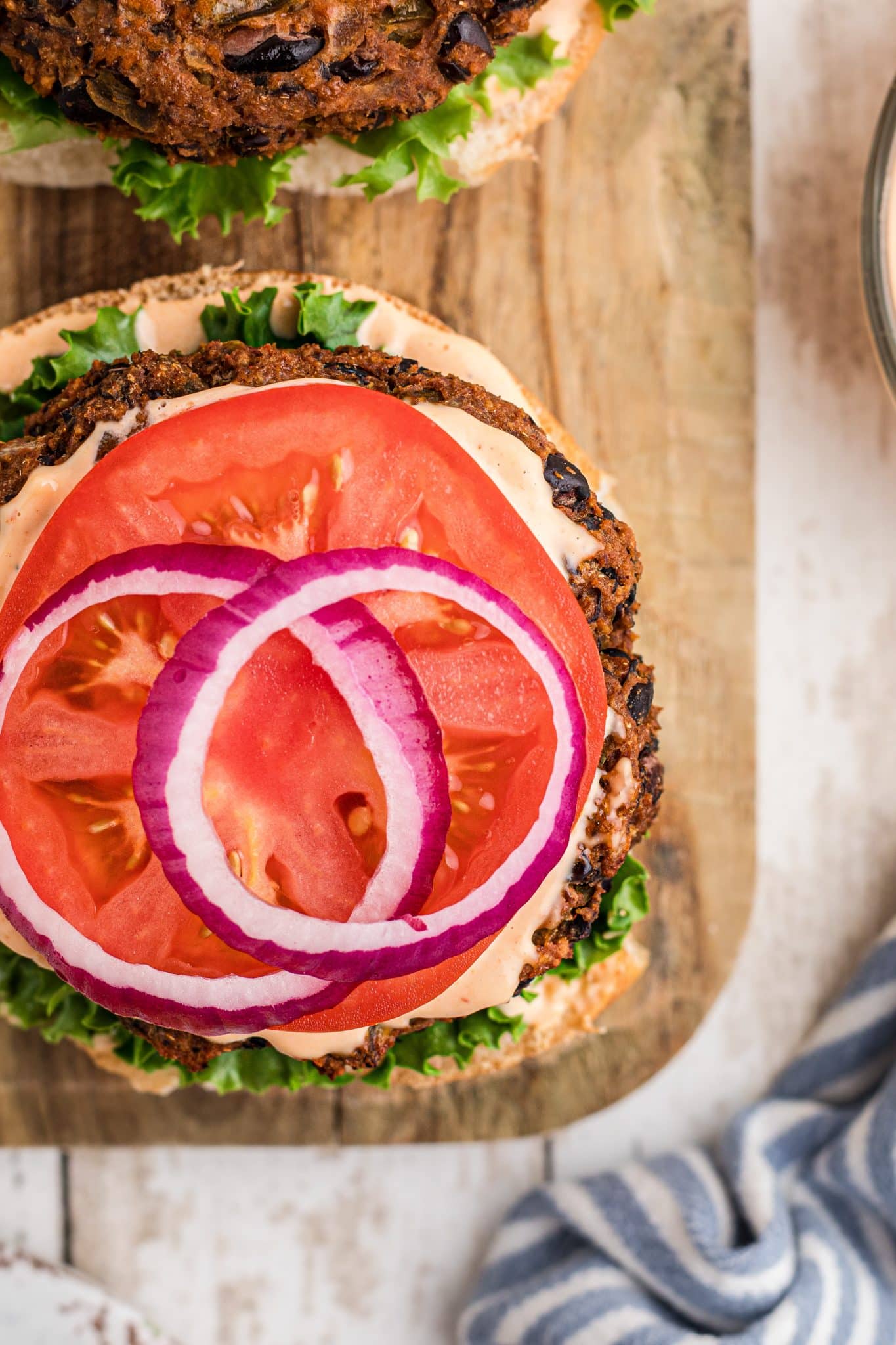 Hamburger bun layered with lettuce, baked black bean burger patty, chipotle mayonnaise, sliced tomato and two slices of red onion.