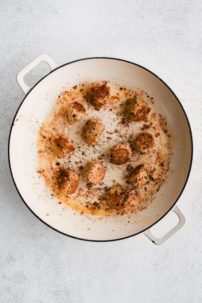 Large skillet filled with eleven crispy pan-seared buffalo chicken meatballs.