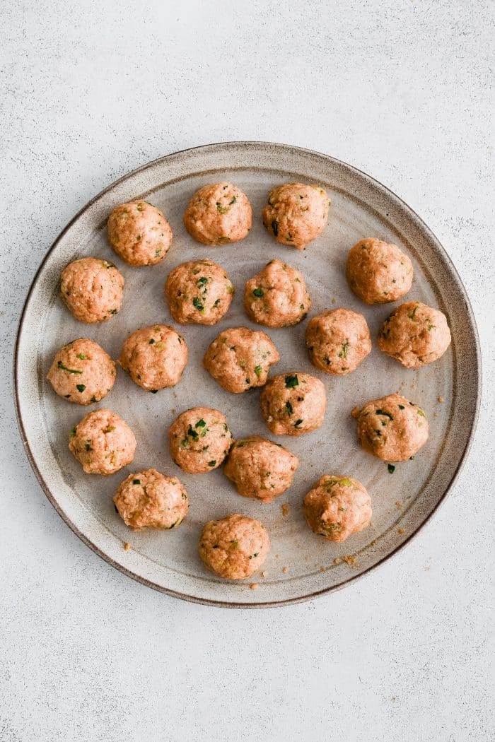 Large round plate filled with formed buffalo chicken meatballs.