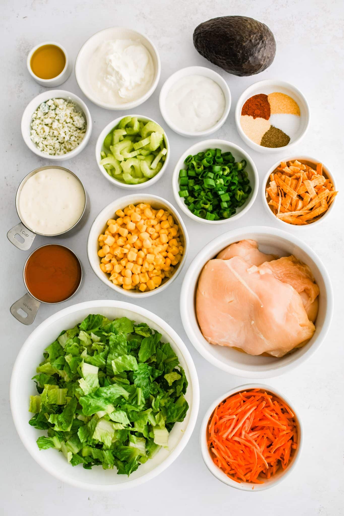 All of the ingredients for buffalo chicken salad presented in individual measuring cups and ramekins.