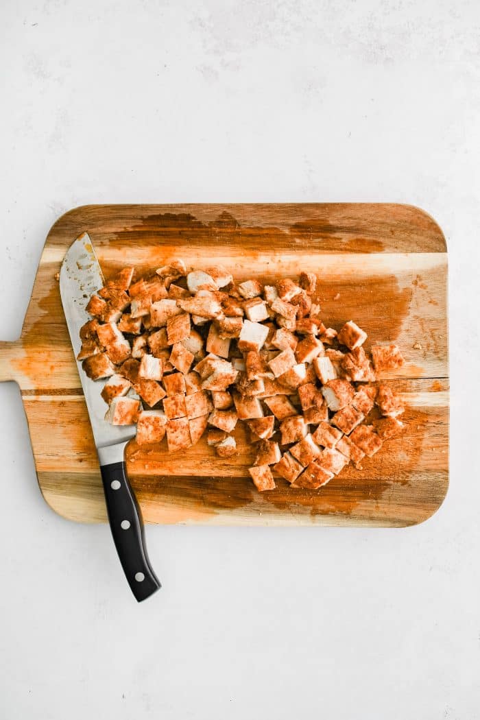 Chopped chicken breast on a large wooden cutting board.