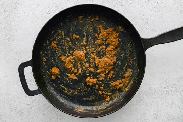 Cajun-spiced roux cooking over medium heat in a large cast iron skillet.