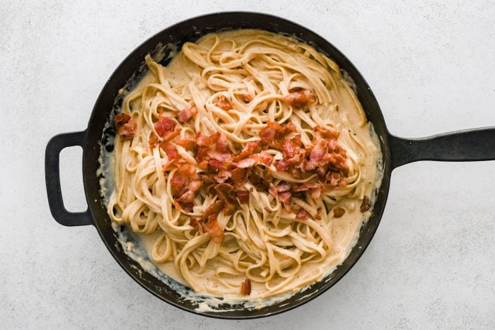 Al dente fettuccine pasta and crispy cooked bacon bits added to simmering Cajun Alfredo sauce.