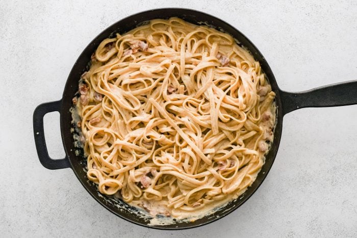 Homemade fettuccine Cajun alfredo in a large black cast iron skillet.