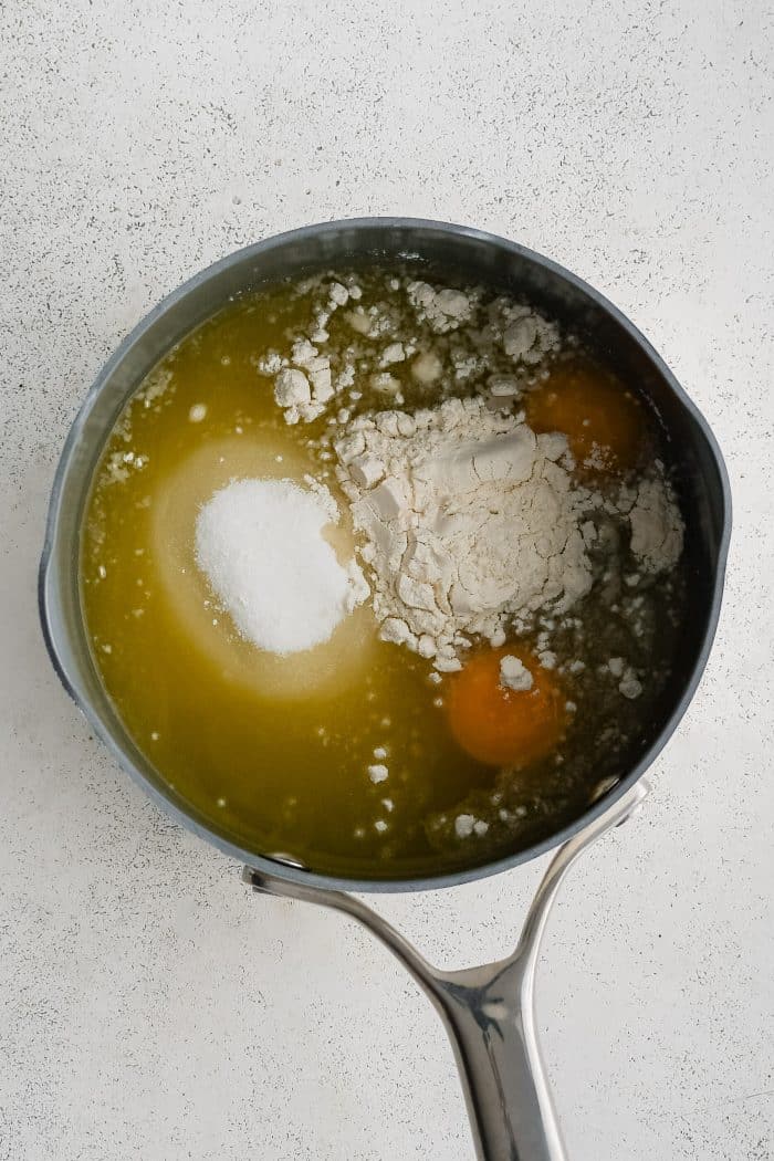 Medium saucepan filled with pineapple juice, sugar, egg yolks, lemon juice, flour, and salt.