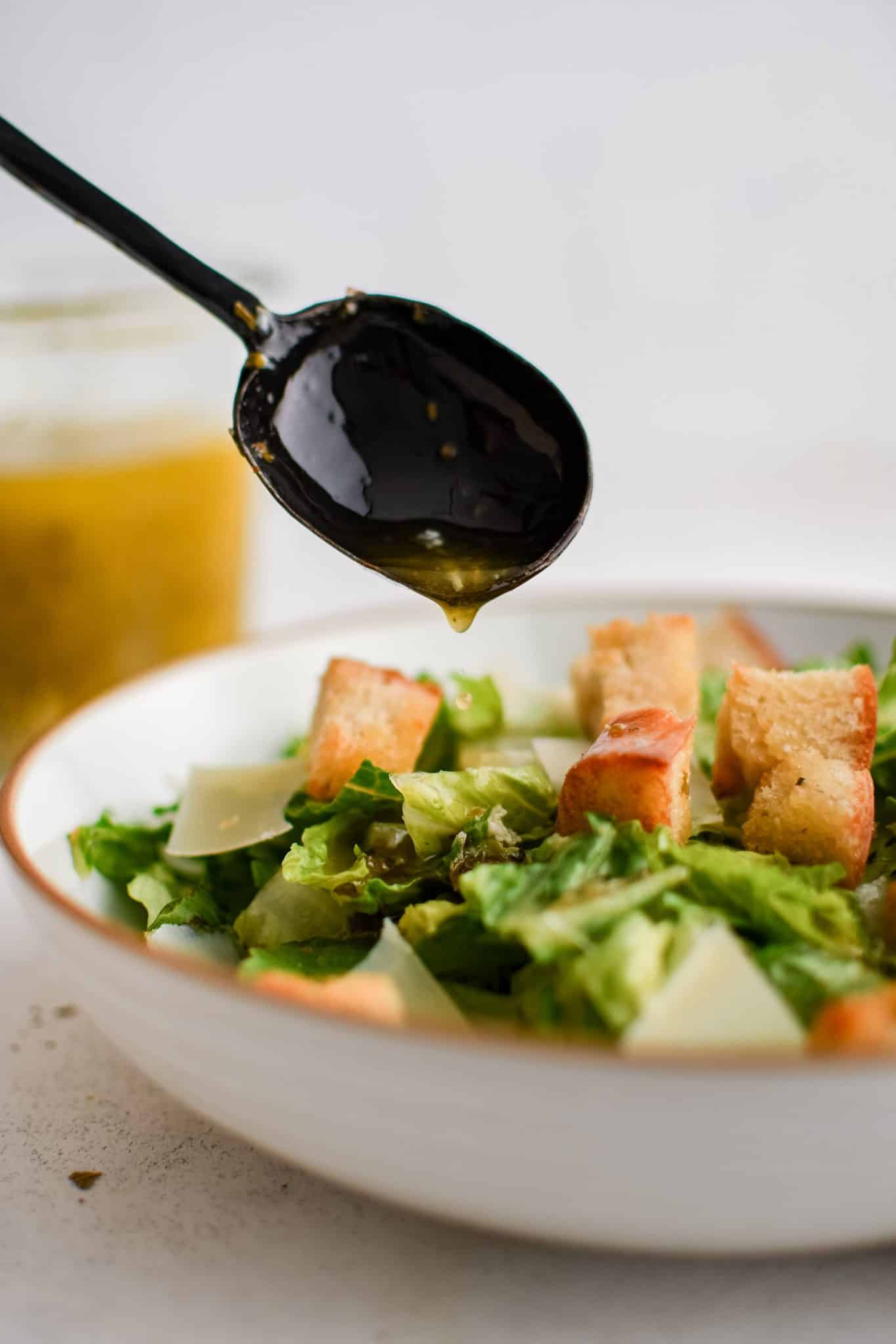 Drizzling homemade Italian dressing over a small house salad with croutons.