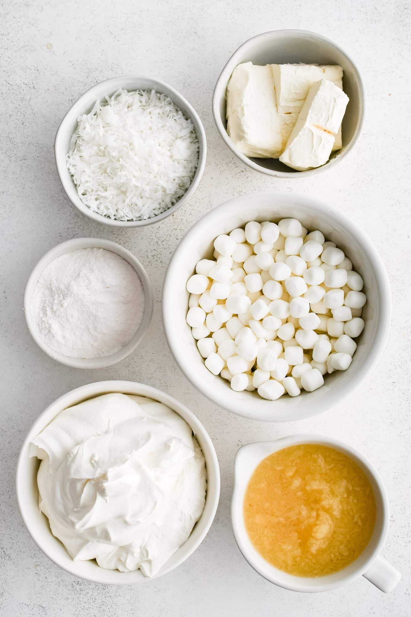 All of the ingredients for homemade pineapple fluff presented in individual measuring cups and ramekins.