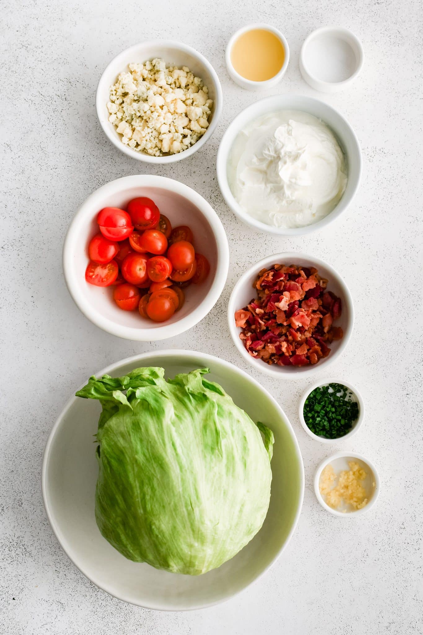 All of the ingredients for wedge salad presented in individual measuring cups and ramekins.