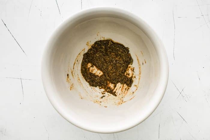 A bowl with the seasoning mixture of olive oil, baking powder, and poultry seasoning thoroughly mixed into a paste.