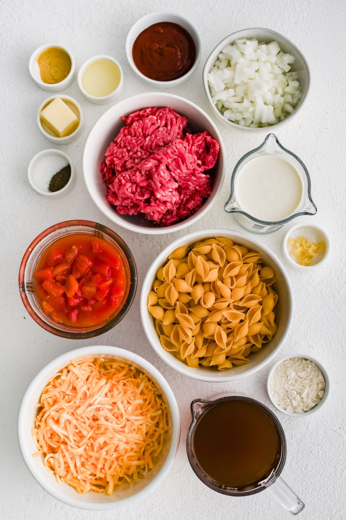 All of the ingredients for Cheeseburger Casserole presented in individual measuring cups and ramekins.