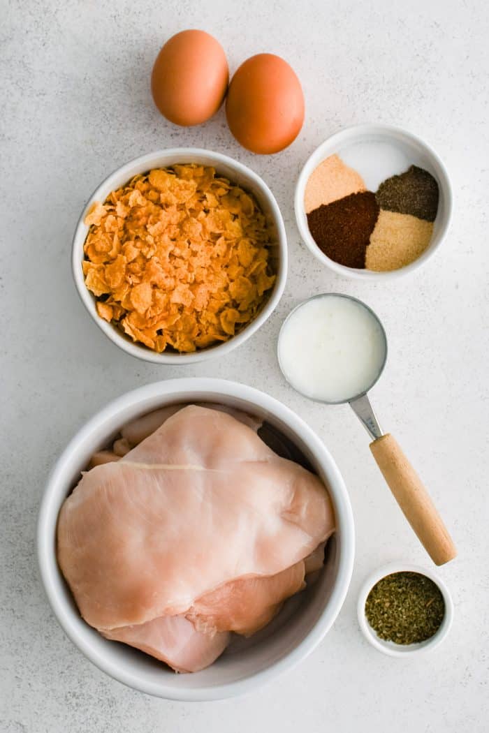 All of the ingredients for cornflake chicken presented in individual measuring cups and ramekins.