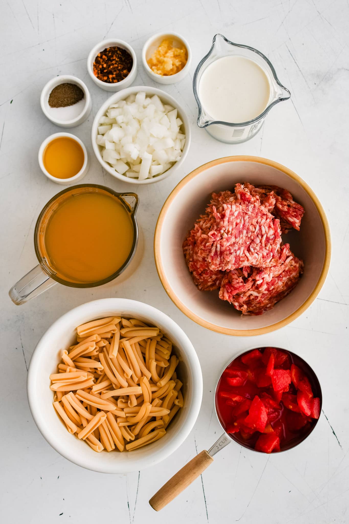 All of the ingredients for Italian sausage soup presented in individual measuring cups and ramekins.