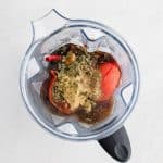 Large blender filled with rehydrated red Mexican chiles, two whole boiled tomatoes, a whole onion, whole garlic cloves, Mexican oregano and cumin with chicken broth and rehydrating liquid.