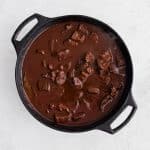 Homemade chile colorado simmering in a large cast iron pot.