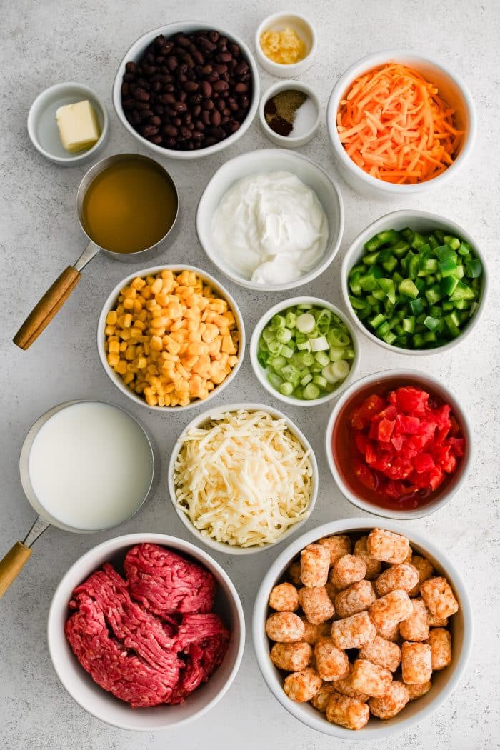 All of the ingredients needed to make creamy cowboy casserole with tater tot topping in individual measuring cups and ramekins.