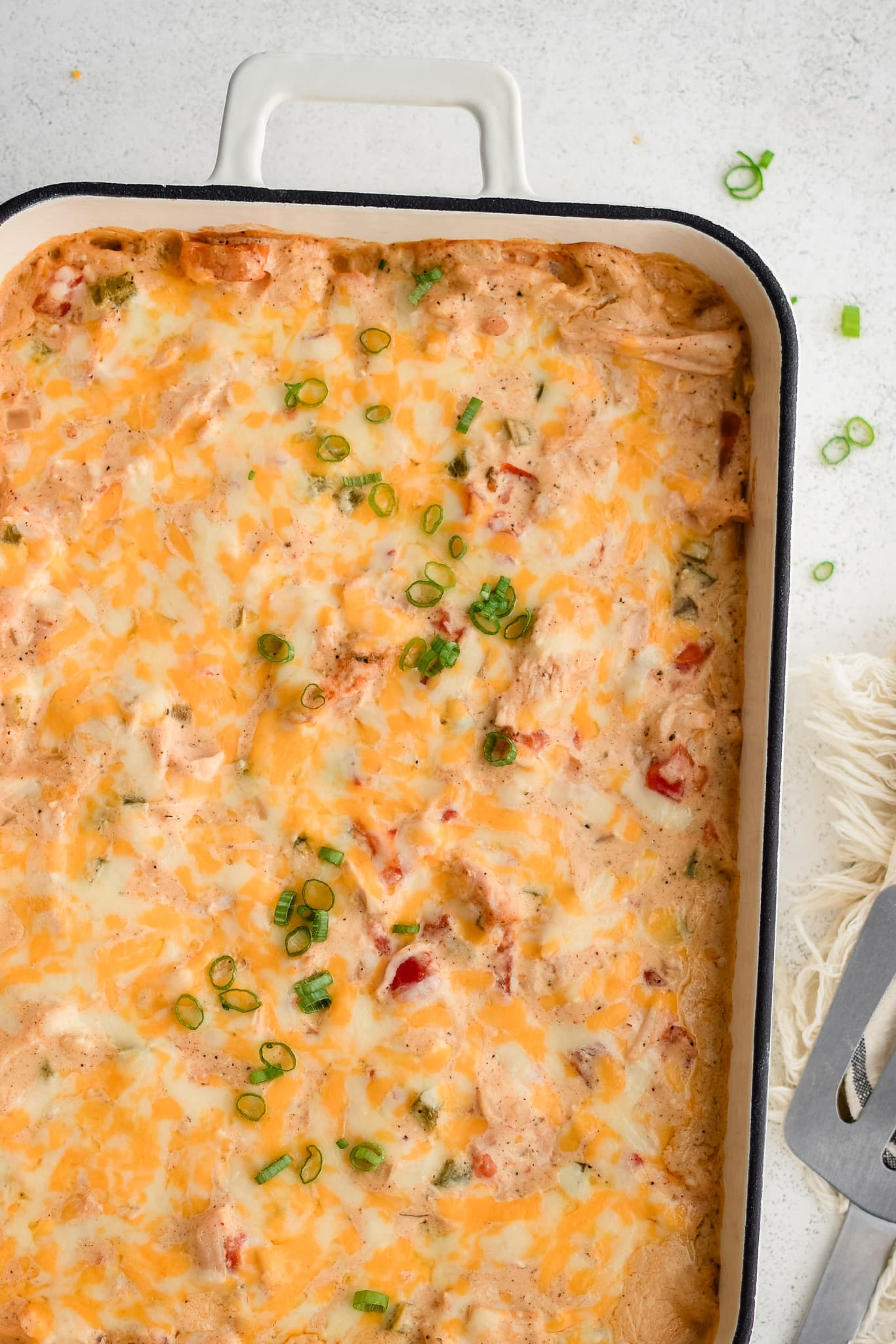 Baked King Ranch chicken casserole with a top layer of golden melty cheese and a garnish of sliced green onions.