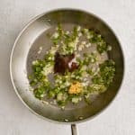 Minced garlic, chili powder, salt, and black pepper added to a large skillet with softened diced green bell peppers and diced white onions.