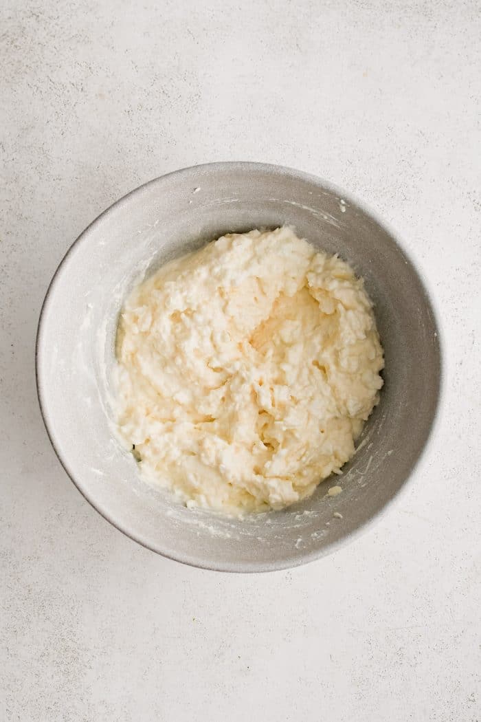 Large mixing bowl filled with combined shredded mozzarella, parmesan, ricotta, and cottage cheese.