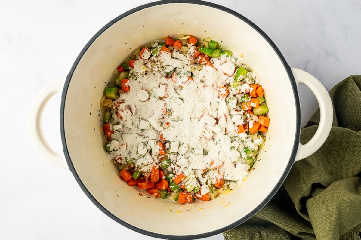After melting the remaining 2 tablespoons of butter into the vegetables, all-purpose flour is sprinkled over the mixture. The flour is stirred into the vegetables and cooked briefly before adding chicken stock, helping create a smooth, lightly thickened broth.