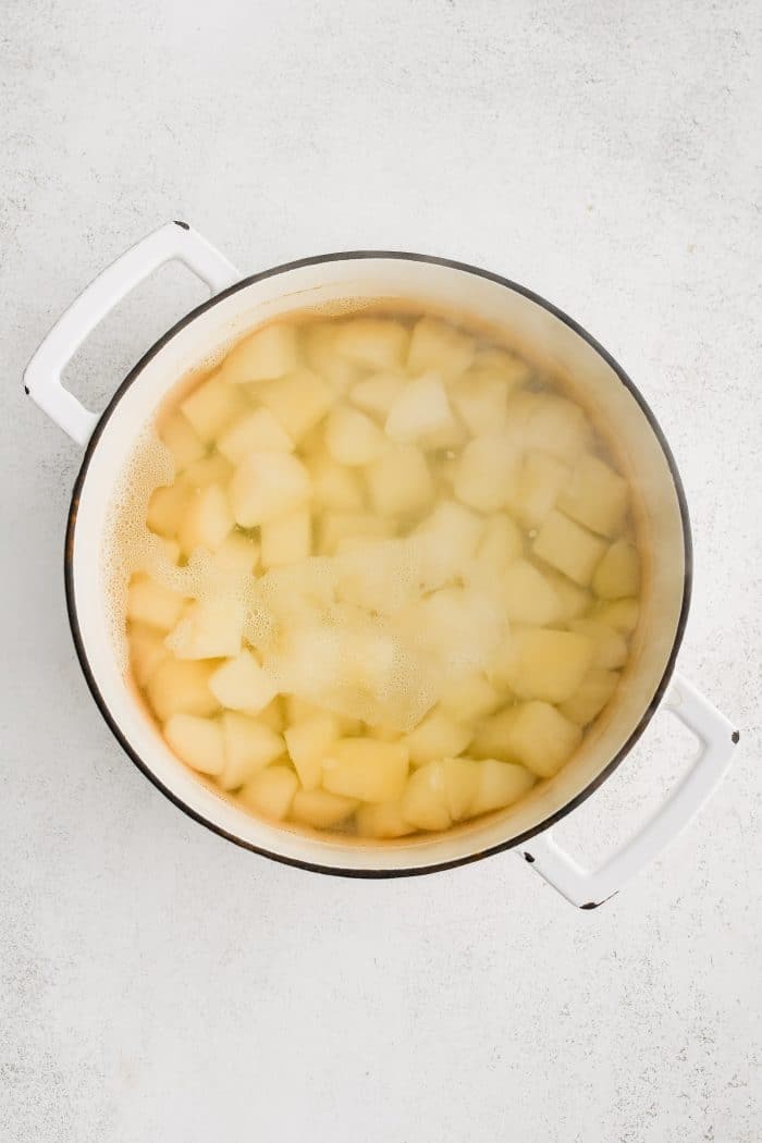 Large stockpot filled with peeled and diced potatoes simmering in boiled water.