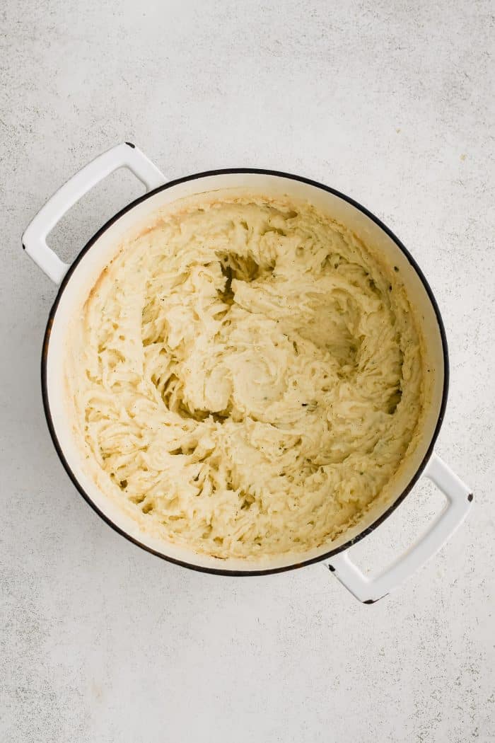 Large stock pot filled with creamy herb and garlic infused mashed potatoes.