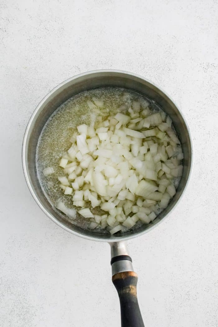 Diced onion added to a saucepan filled with melted butter.