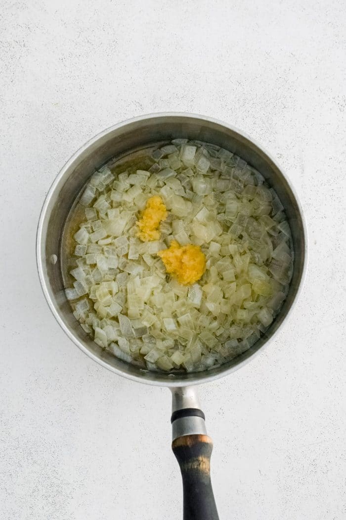 Fresh minced garlic added to a medium saucepan with softened onions in butter.