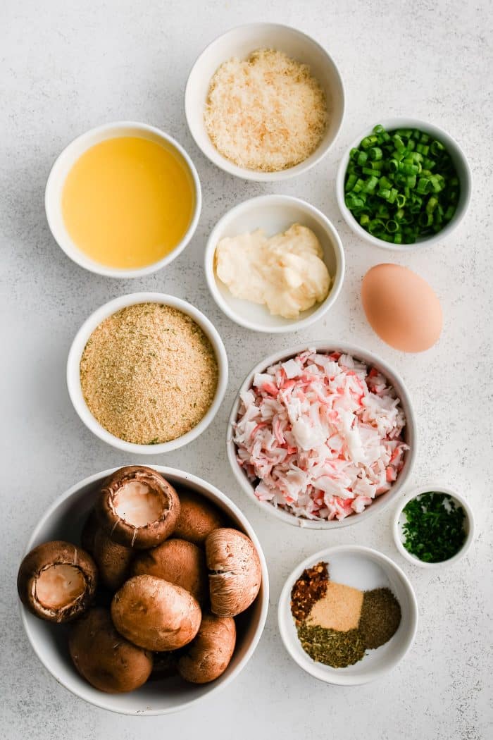 All of the ingredients needed to make crab stuffed mushrooms in individual measuring cups and ramekins.