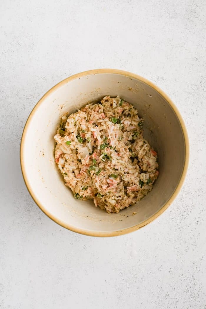 Medium mixing bowl filled with mixed together crab mixture for crab stuffed mushrooms.