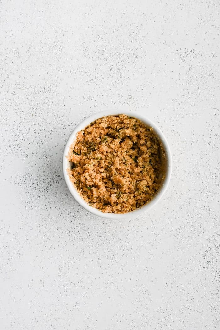 Small white bowl filled with crispy buttery topping for crab stuffed mushrooms.