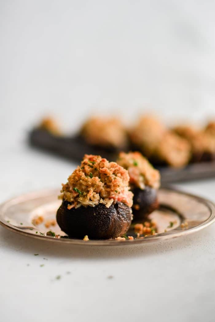 Small silver serving plate with two crab stuffed mushrooms.