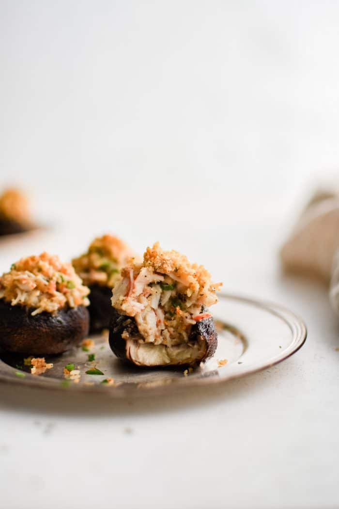 Small silver serving plate with three crab stuffed mushrooms.