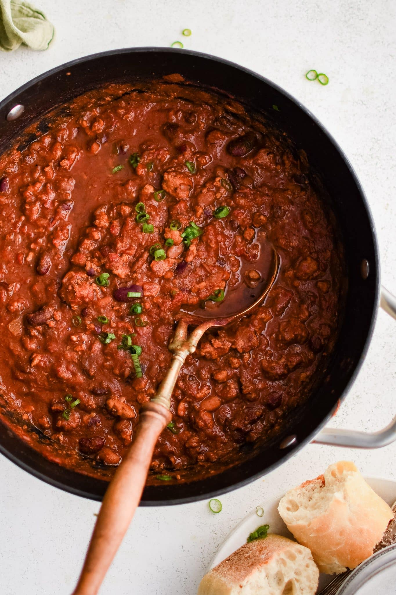 Large pot filled with simmering turkey chili with kidney and pinto beans and garnished with chopped green onions.