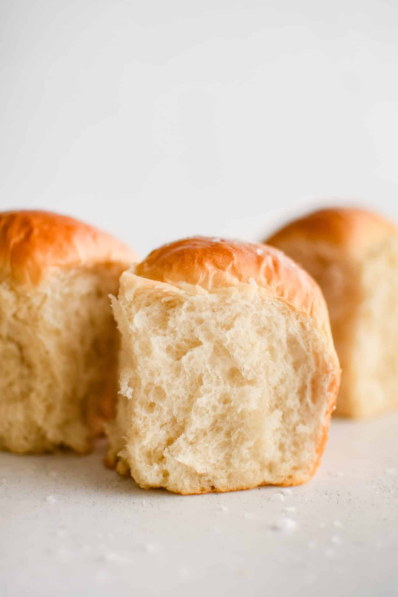 Three perfectly soft, fluffy, and flaky dinner rolls with buttery golden tops.