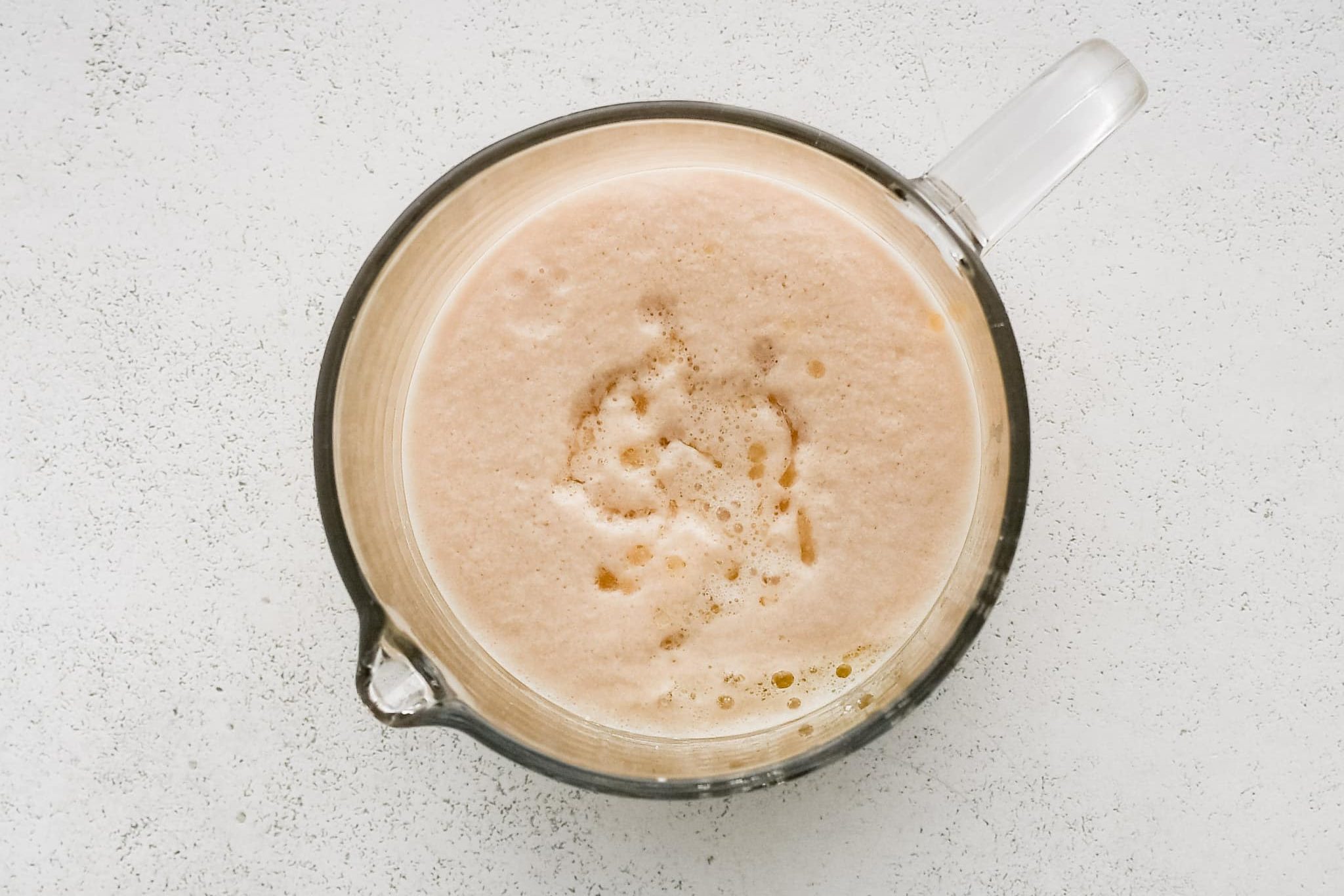 Foaming, bubbly activated yeast in a glass measuring cup.