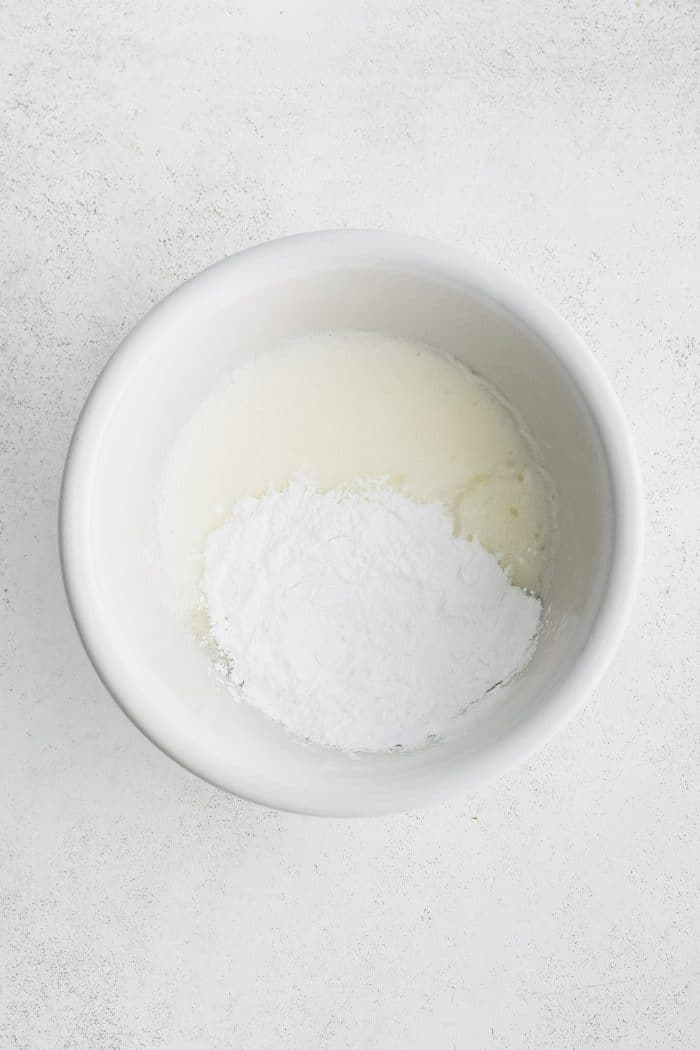 White bowl with fluffy whisk egg whites and club soda with tapioca flour.