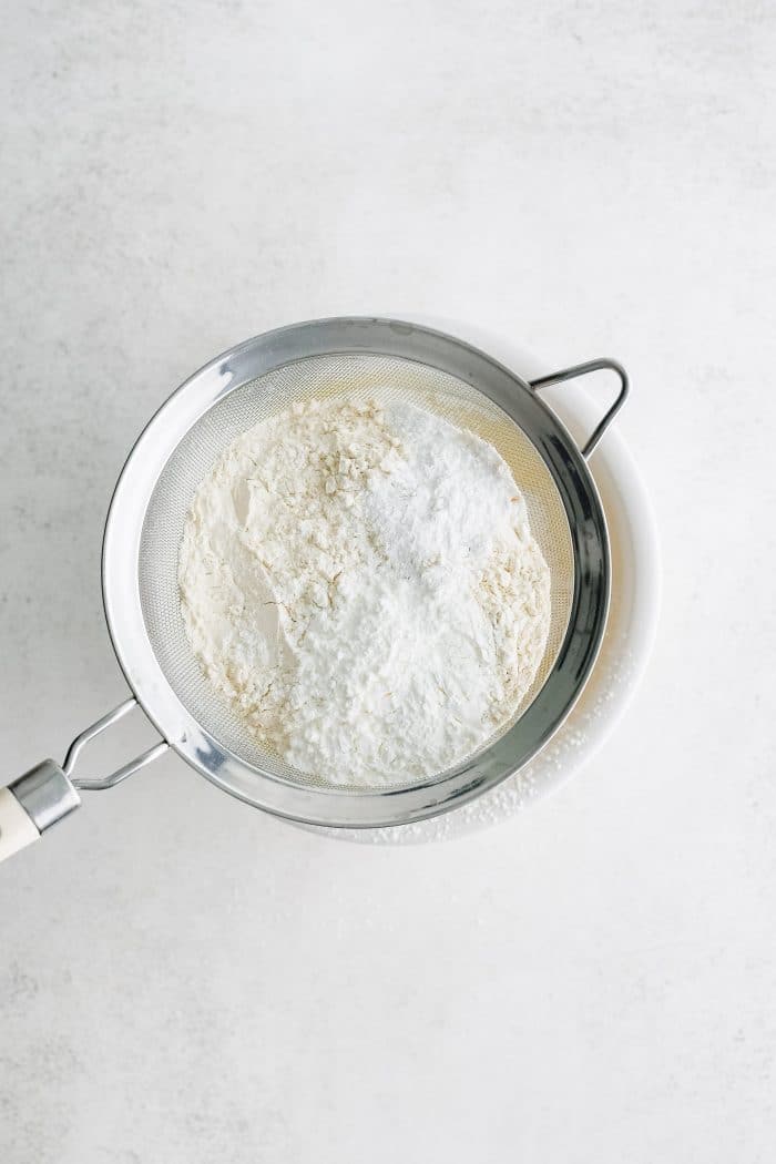 Sifting flour, salt, cornstarch, and baking powder into a white mixing bowl.