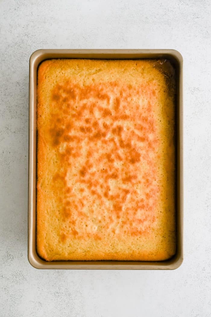 A perfectly golden baked vanilla cake in a 9x13 inch cake pan.