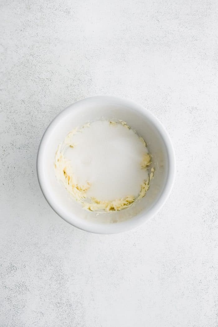 Mixing bowl filled with whipped butter and granulated sugar.