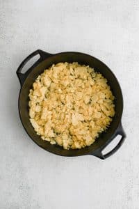 Large cast iron skillet filled with a thin layer of crushed potato chips.