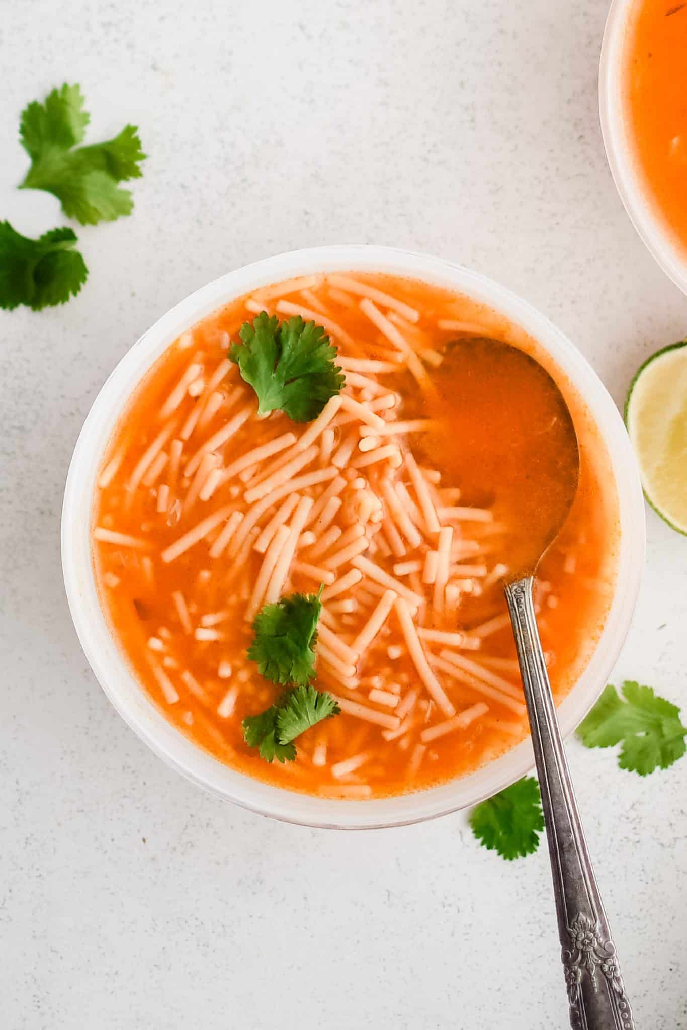 White soup bowl filled with Sopa De Fideo (Mexican Noodle Soup) made with a light tomato broth and small fideo noodles.