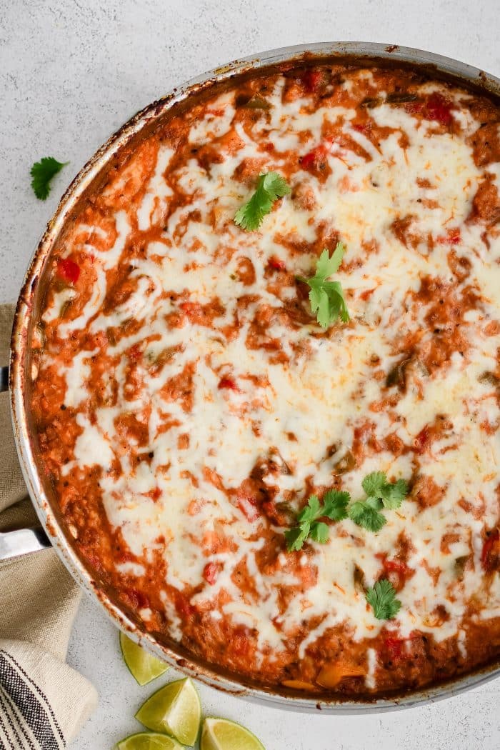 Large oven-safe skillet filled with Stuffed Pepper Casserole hot out of the oven and topped with gooey melted Monterey Jack cheese and garnished with fresh cilantro.